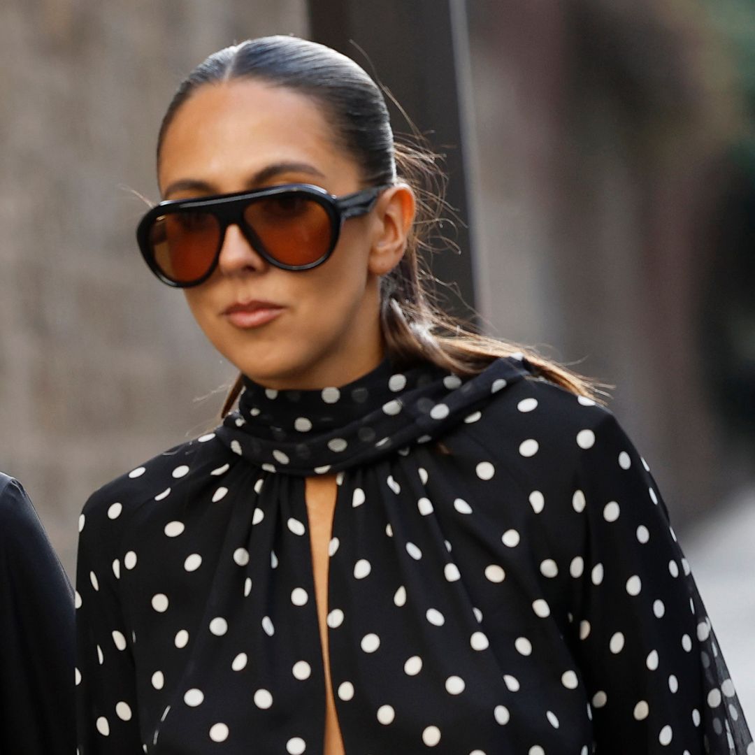 A woman at fashion week, wearing black and sunglasses, with very glowy skin - merit great skin instant glow serum